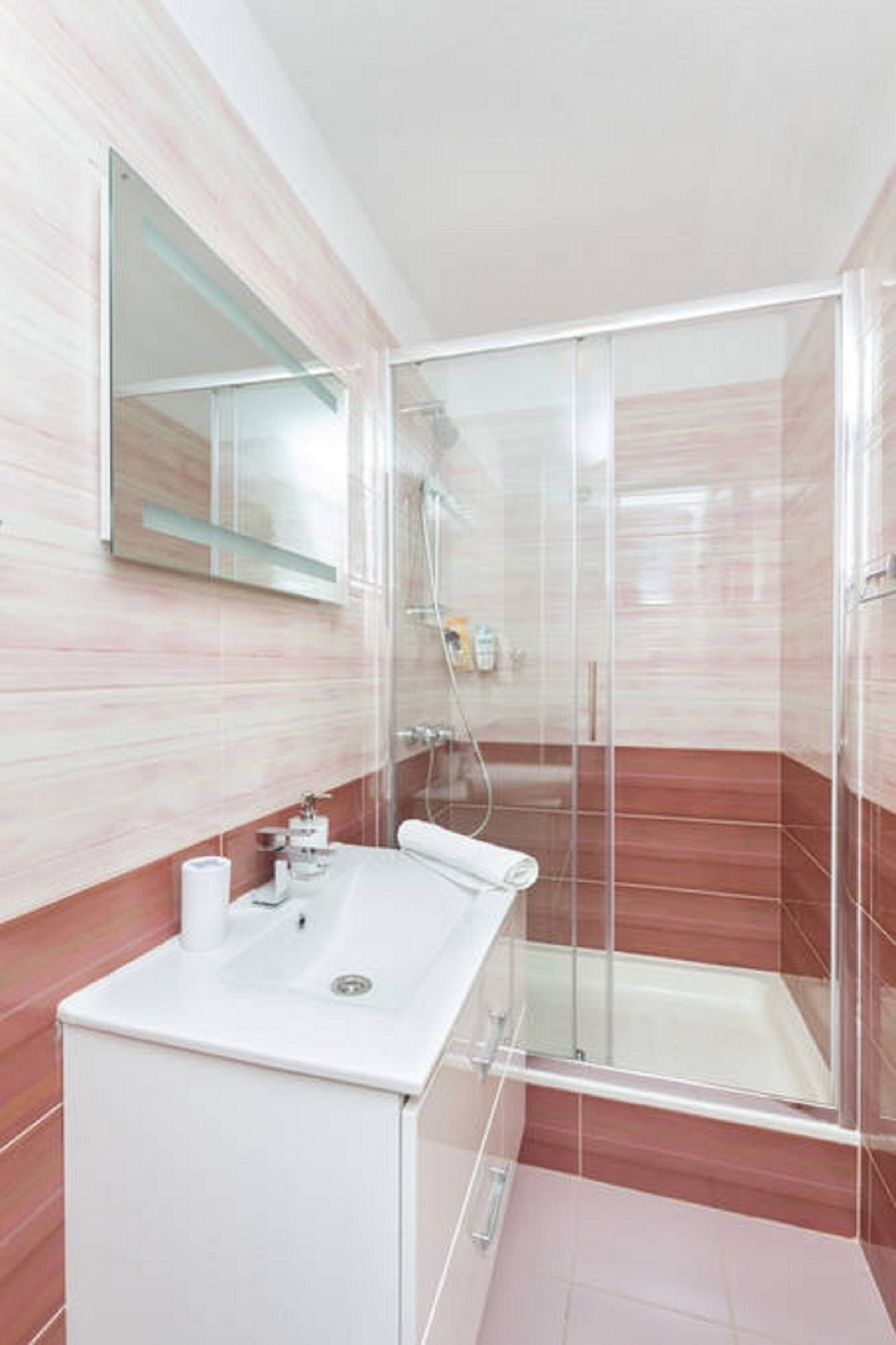 Un baño moderno con cabina de ducha de vidrio, un lavabo blanco y un espejo sobre él.