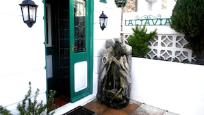 A building entrance with a green door, a sign reading "CANCIES", and a stone wall with a hanging plant. - The Altavia Hotel (Sandown)