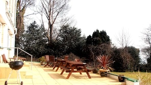 A patio with outdoor furniture, a barbecue grill, and steps leading to a building. - The Altavia Hotel (Sandown)