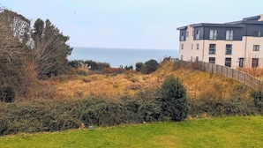 A grassy field with a building in the background. - The Altavia Hotel (Sandown)