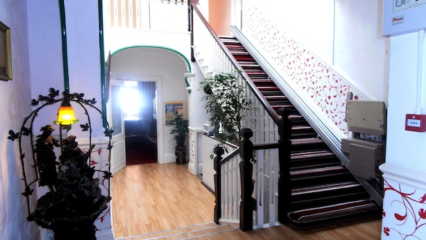 A staircase with a red and white railing, wooden flooring, and a wall-mounted light fixture. - The Altavia Hotel (Sandown)