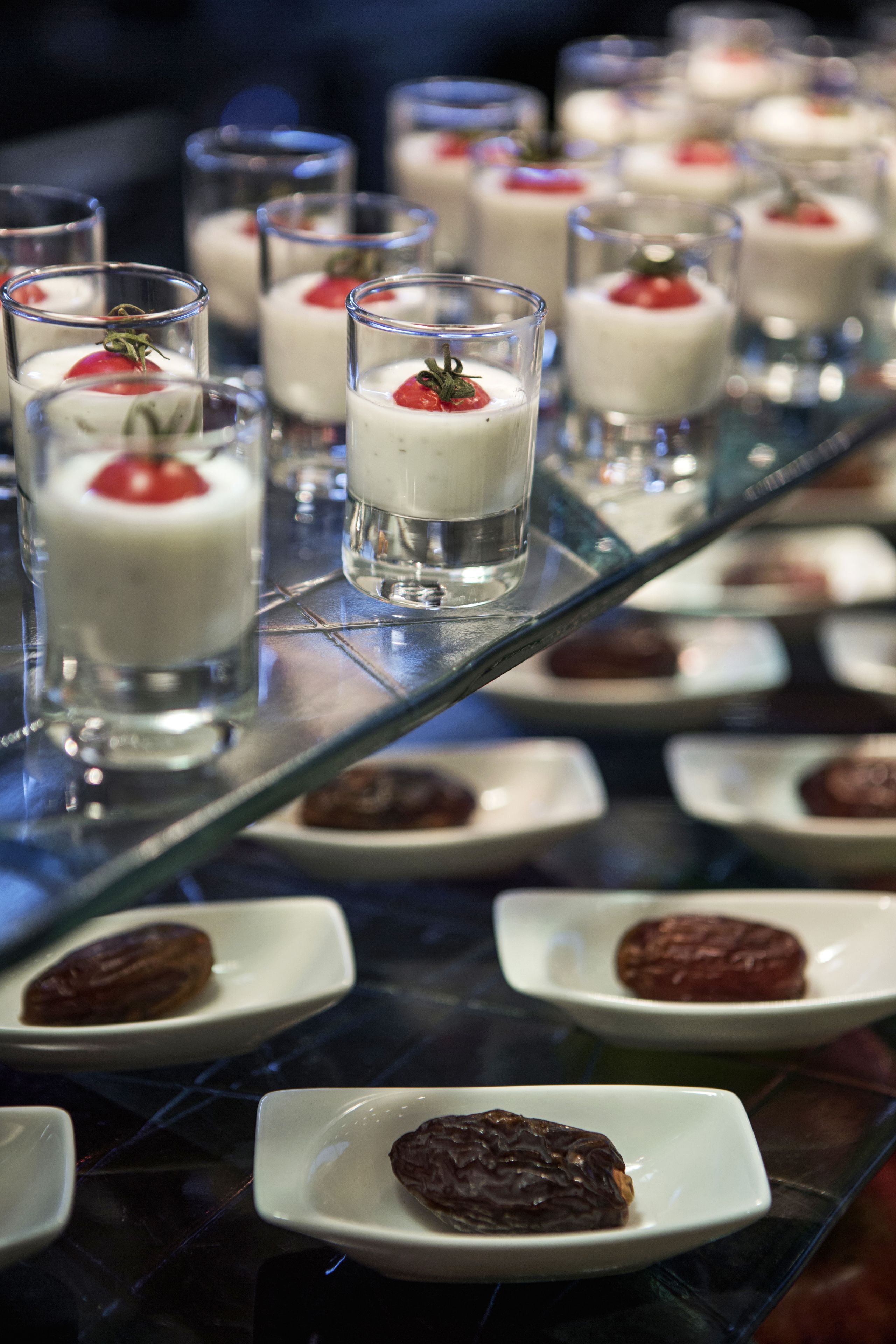 A dessert display with small glass servings topped with a strawberry and a chocolate dessert.