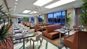 A modern hotel lobby with seating areas, large windows, and indoor plants. - Hilton Garden Inn Istanbul Beylikduzu (Istanbul)