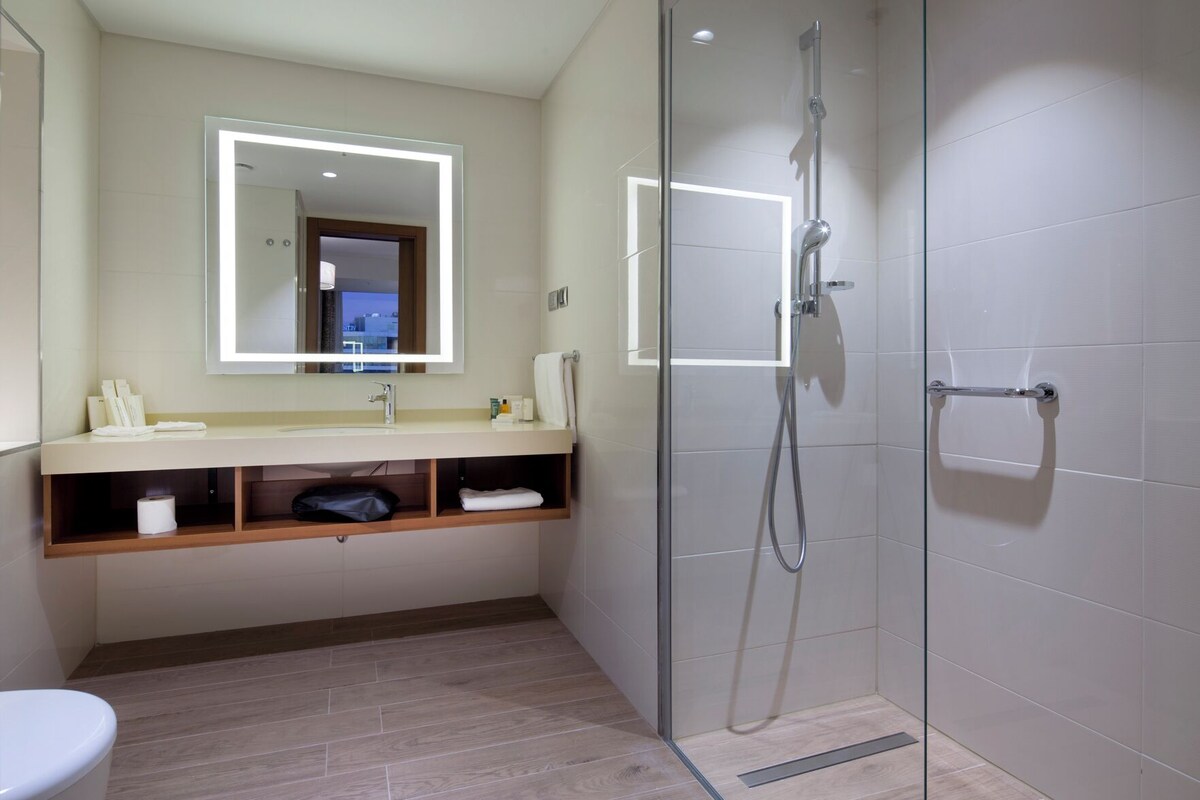 A modern bathroom with a glass shower enclosure, a vanity with a mirror, and a toilet.
