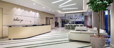A modern reception area with a curved desk, a large potted tree, and a striped floor.
