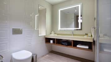 Une salle de bain moderne équipée de toilettes, d’un lavabo, d’un miroir et d’une douche.
