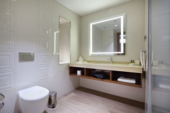 A modern bathroom with a toilet, sink, mirror, and shower.