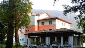 Un hotel amb una zona d'estar exterior coberta, un camí de grava i un paisatge de muntanyes al fons.