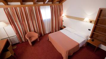 Een hotelkamer met een bed, een stoel, een bureau en een lamp.