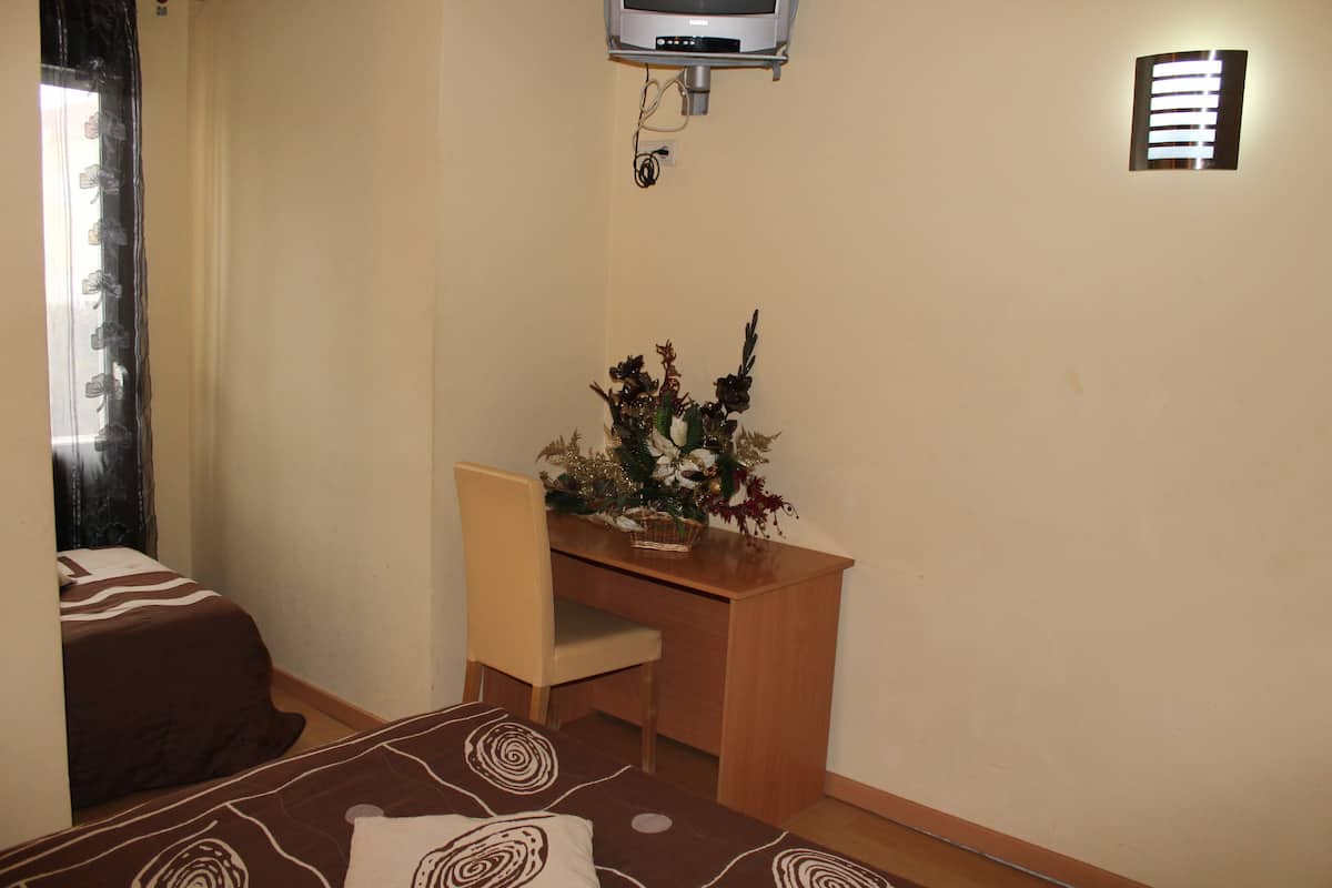 A bedroom with a bed, a desk, a chair, and a small decorative plant.