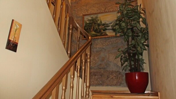 A staircase with wooden balusters, a stone wall, and a red potted plant. - Guest House Estrela (Porto)