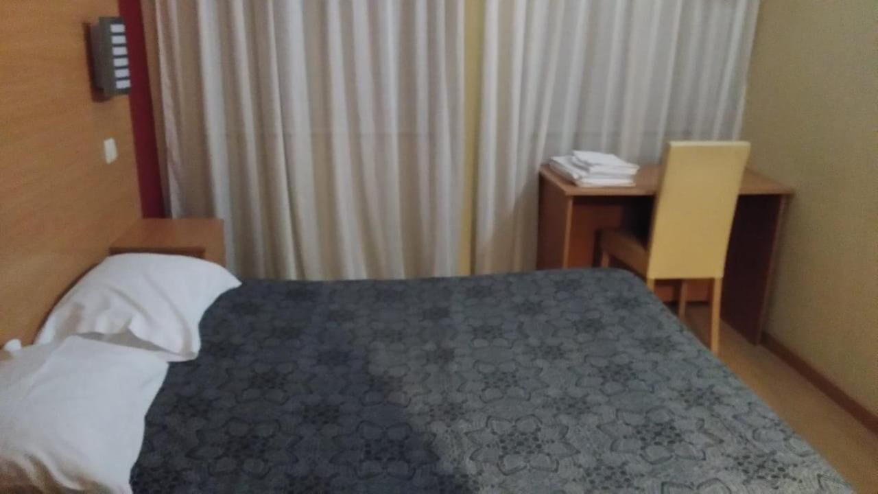 Ein Hotelzimmer mit Bett, Schreibtisch und Stuhl.