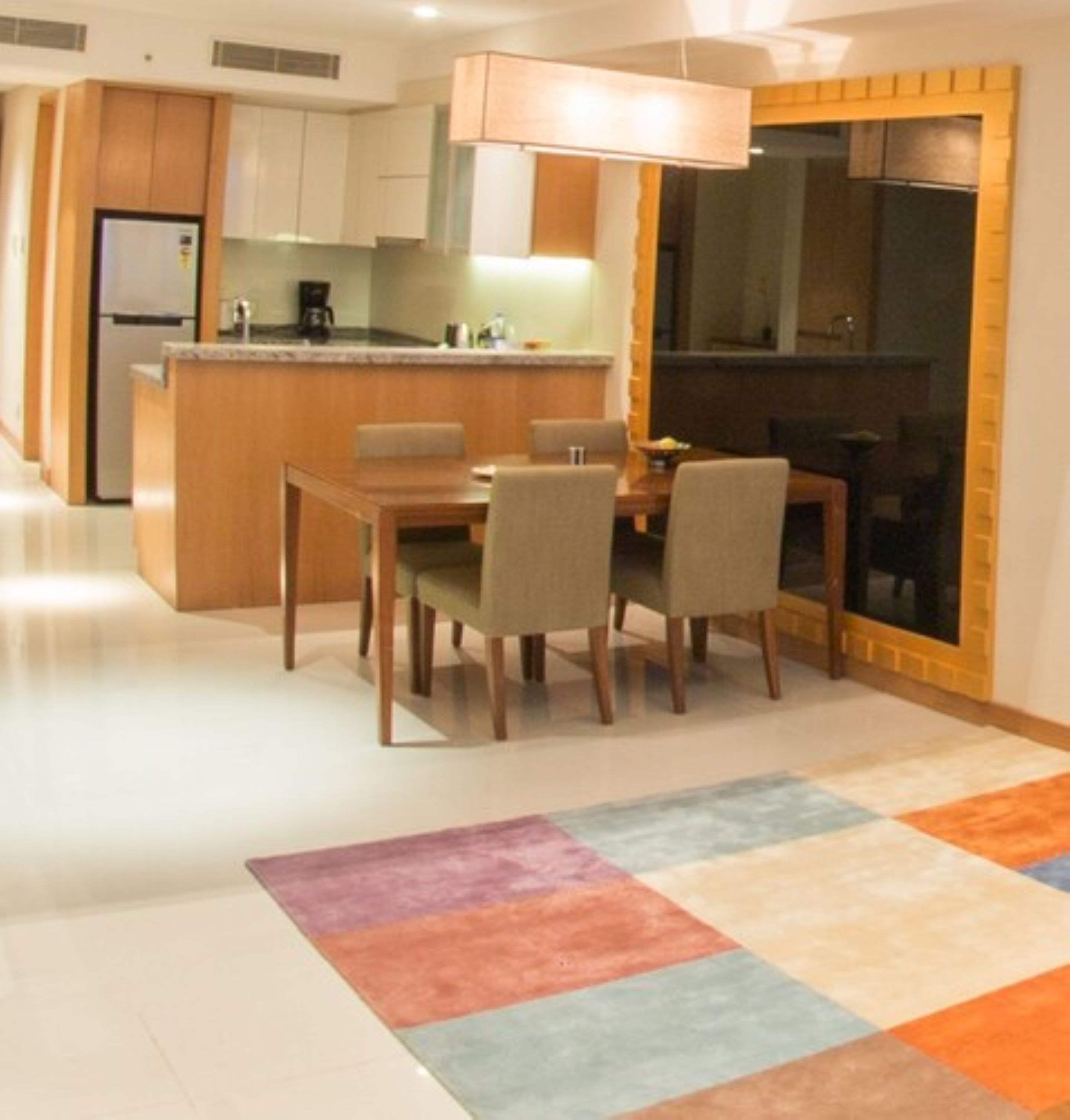 A modern kitchen with wooden cabinets, a built-in refrigerator, and a dining area with a table and chairs.