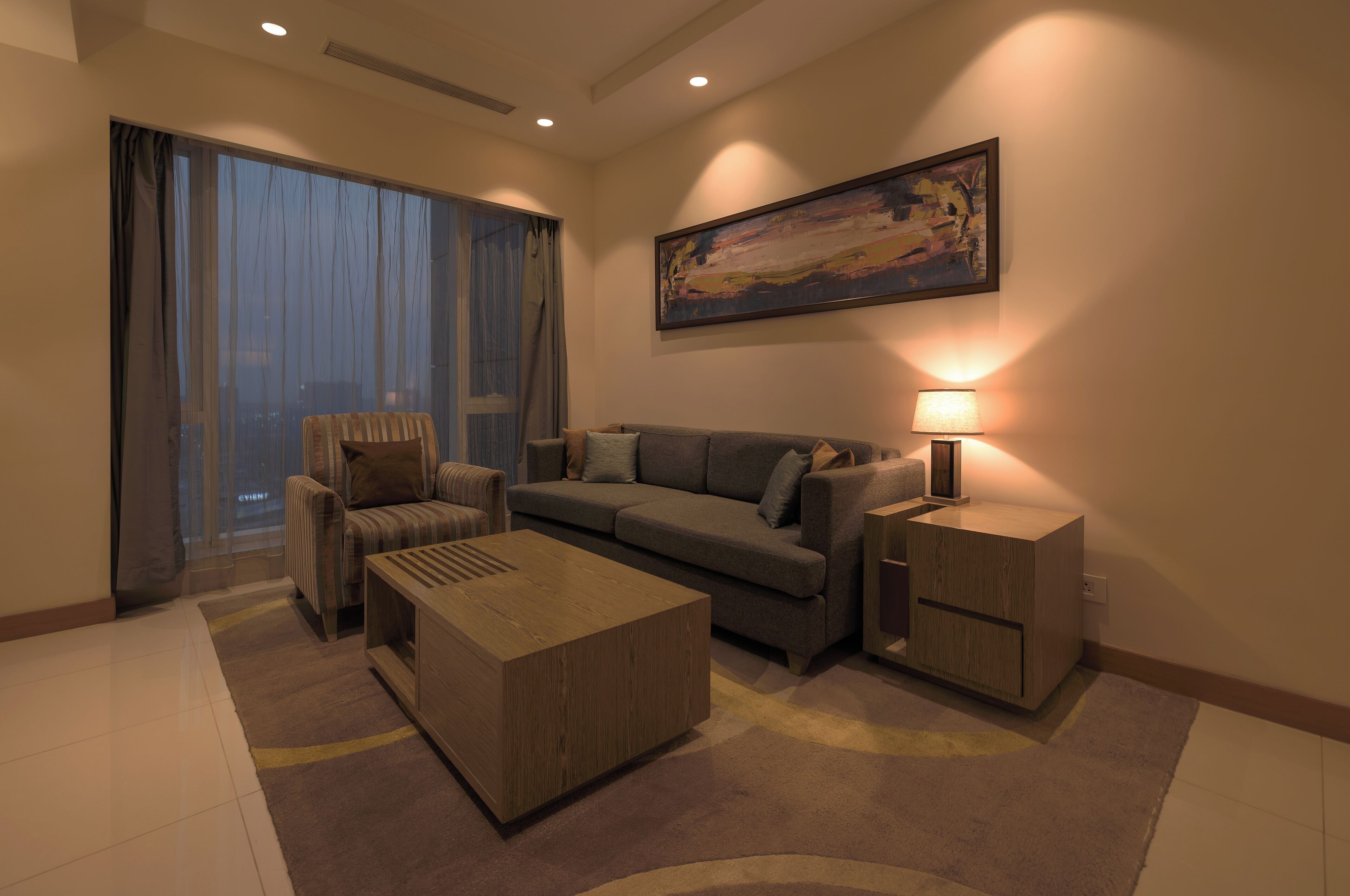 Uma sala de estar moderna com sofá, poltrona, mesa de centro e mesa lateral com abajur.