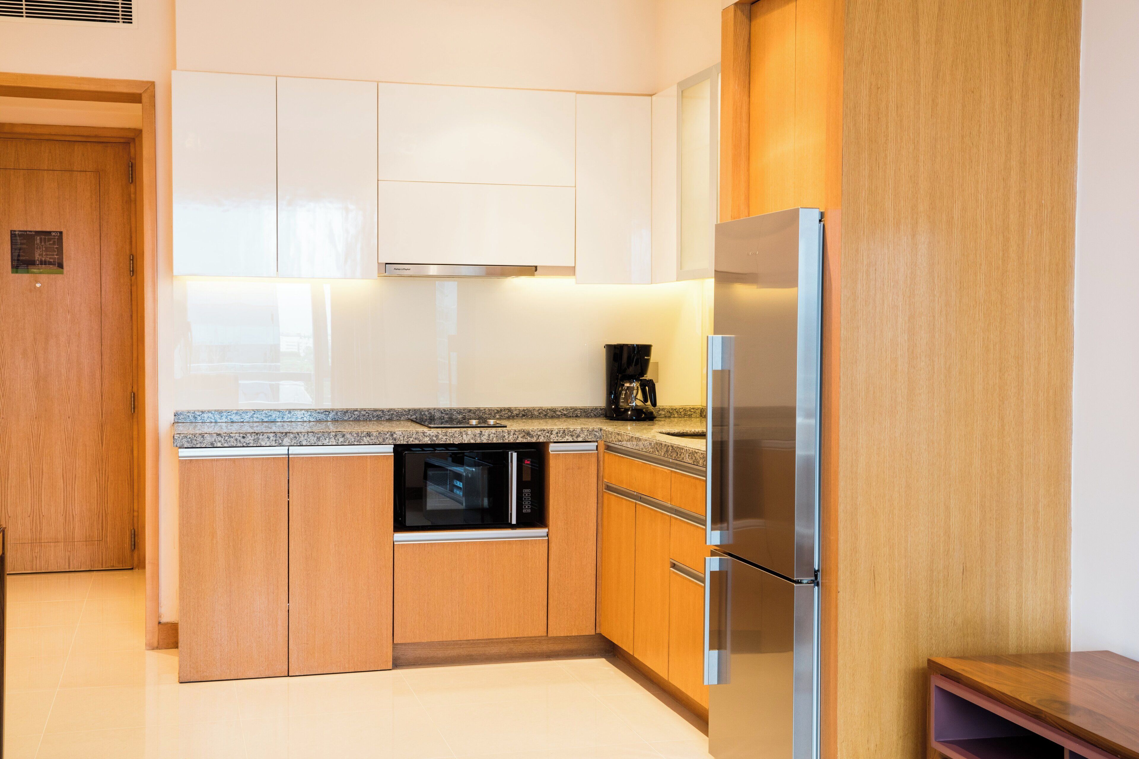 A modern kitchen with wooden cabinets, a built-in oven, a refrigerator, and a coffee maker.