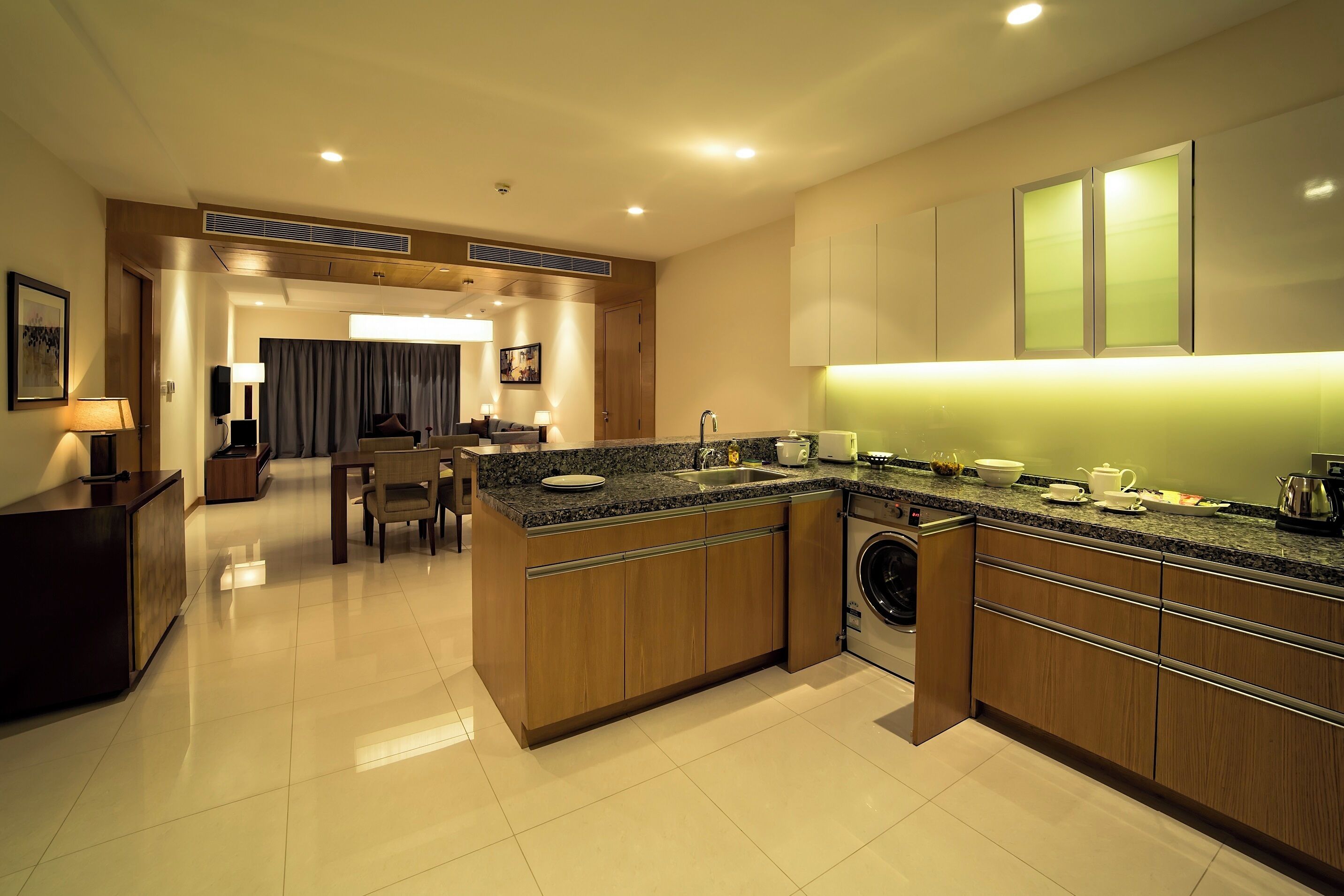 A modern kitchen with granite countertops, wooden cabinets, and a built-in washing machine.