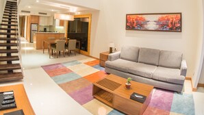 A spacious living area with a high ceiling, a staircase, a dining area, and a kitchen. - Oakwood Residence Kapil Hyderabad (Hyderabad)