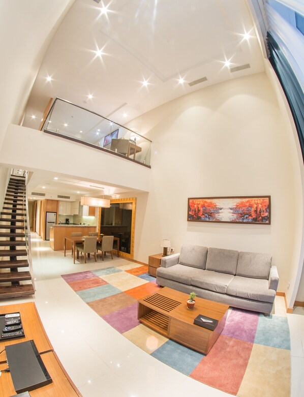 A spacious living area with a high ceiling, a staircase, a dining area, and a kitchen. - Oakwood Residence Kapil Hyderabad (Hyderabad)