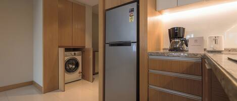 Una cocina moderna con armarios de madera, un refrigerador de acero inoxidable, lavadora, cafetera y tostadora.