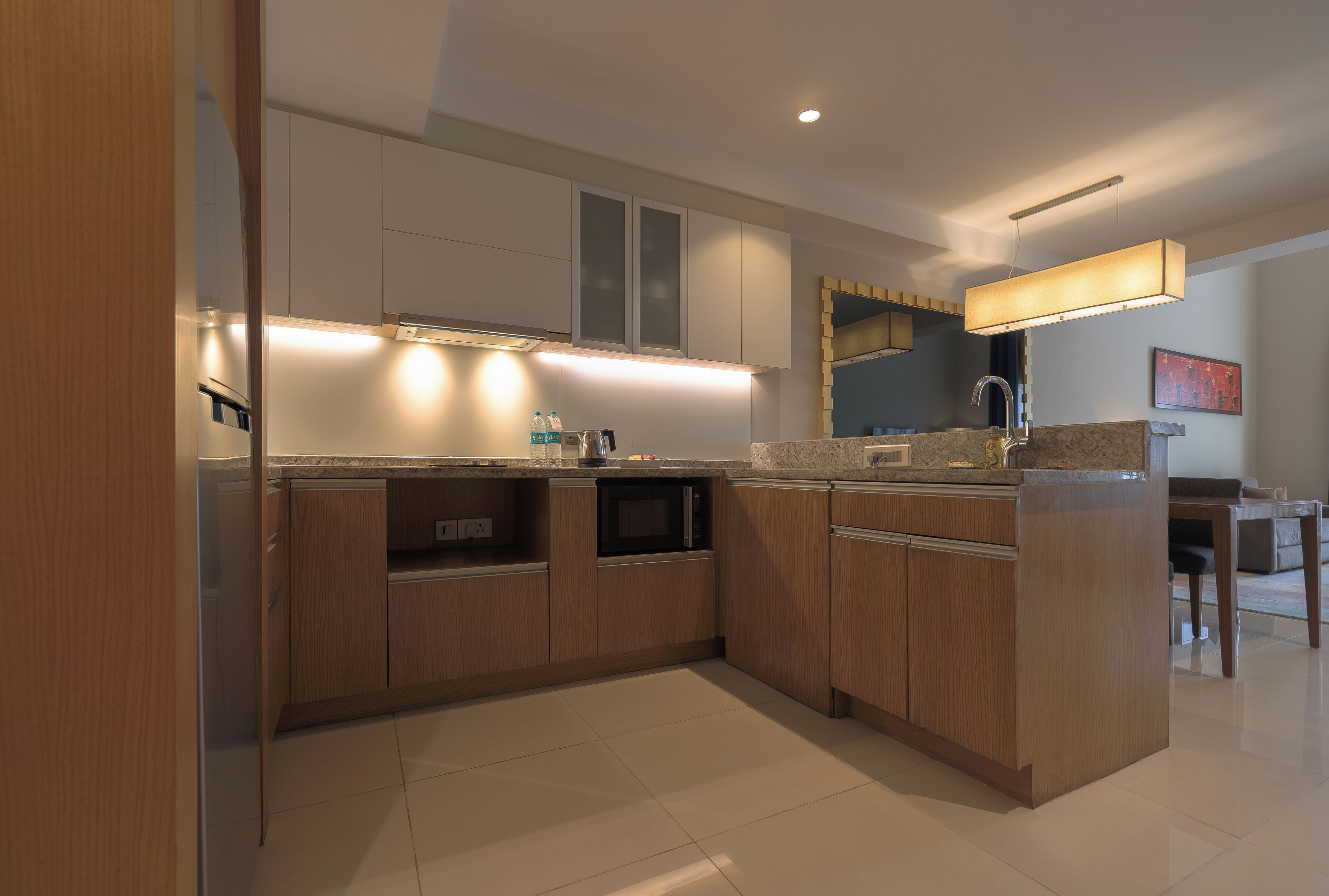 A modern kitchen with wooden cabinets, a built-in microwave, and a large island with a sink.