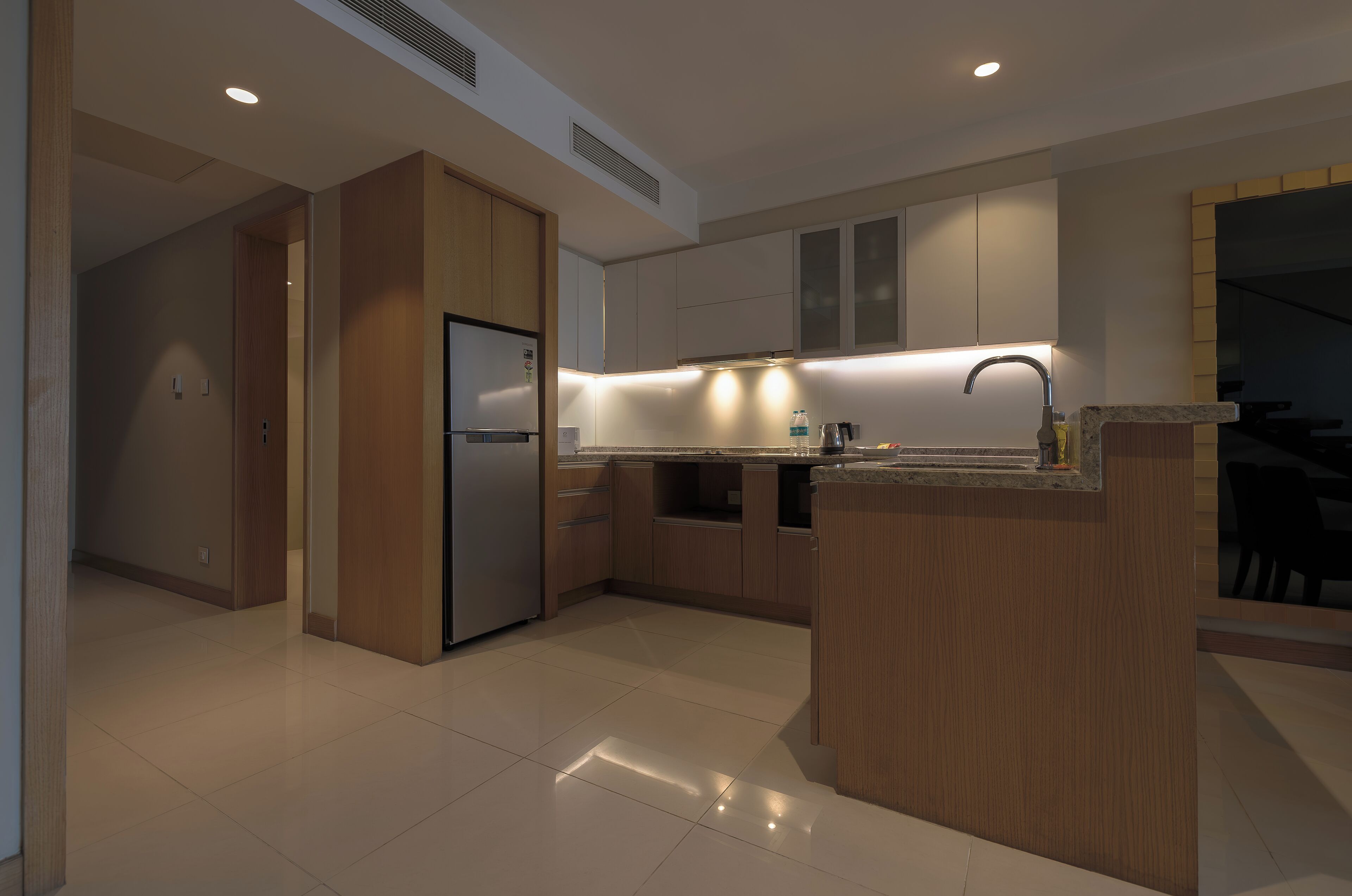 A modern kitchen with wooden cabinets, a built-in refrigerator, and under-cabinet lighting.