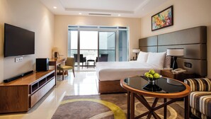 A modern hotel room with a large bed, a flat-screen TV, a dining area, and a balcony with a view. - Oakwood Residence Kapil Hyderabad (Hyderabad)