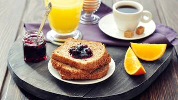 A breakfast tray with toast, jam, orange juice, coffee, and a small jar of jam.