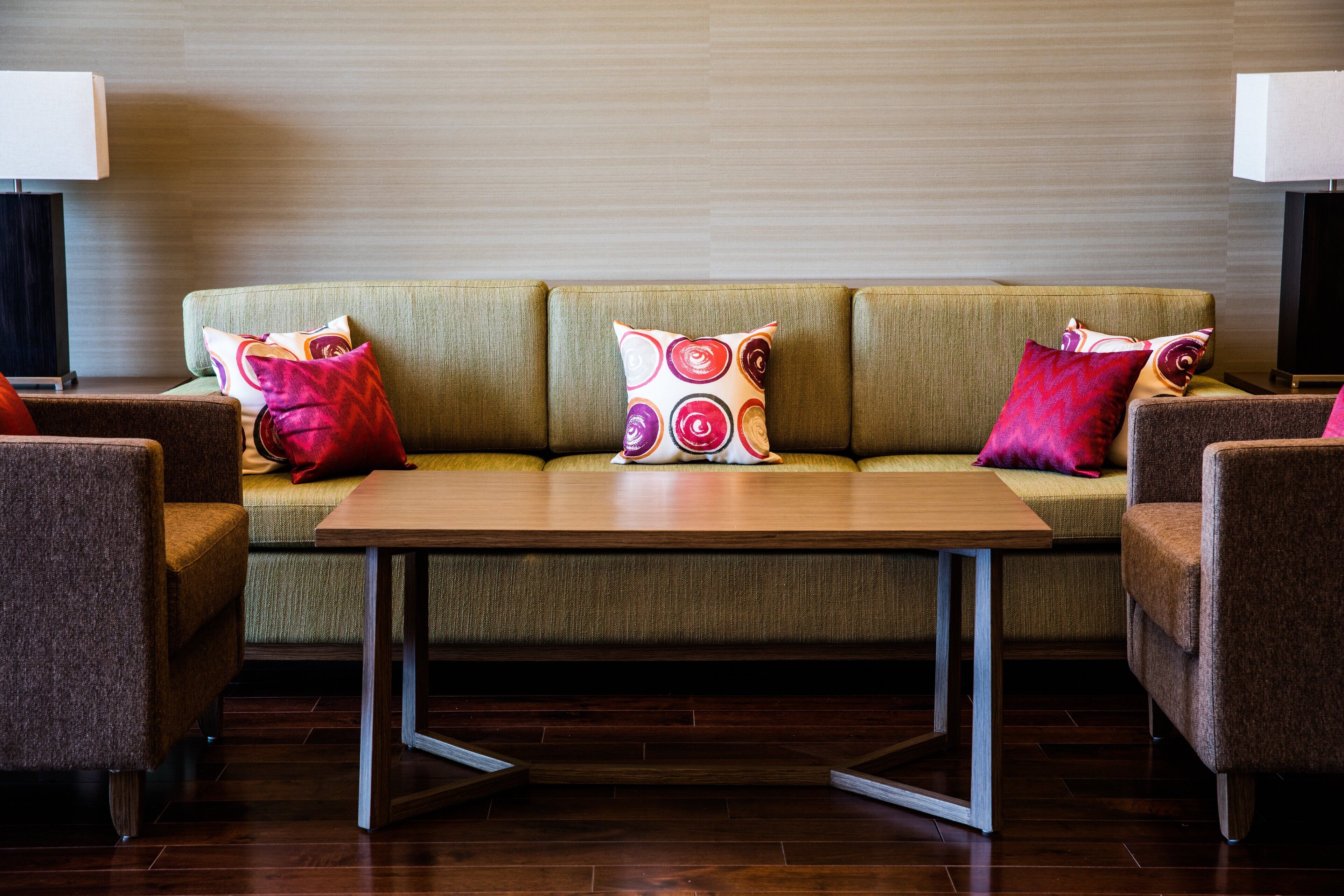 A modern living room with a sofa set, two armchairs, a coffee table, and decorative pillows.