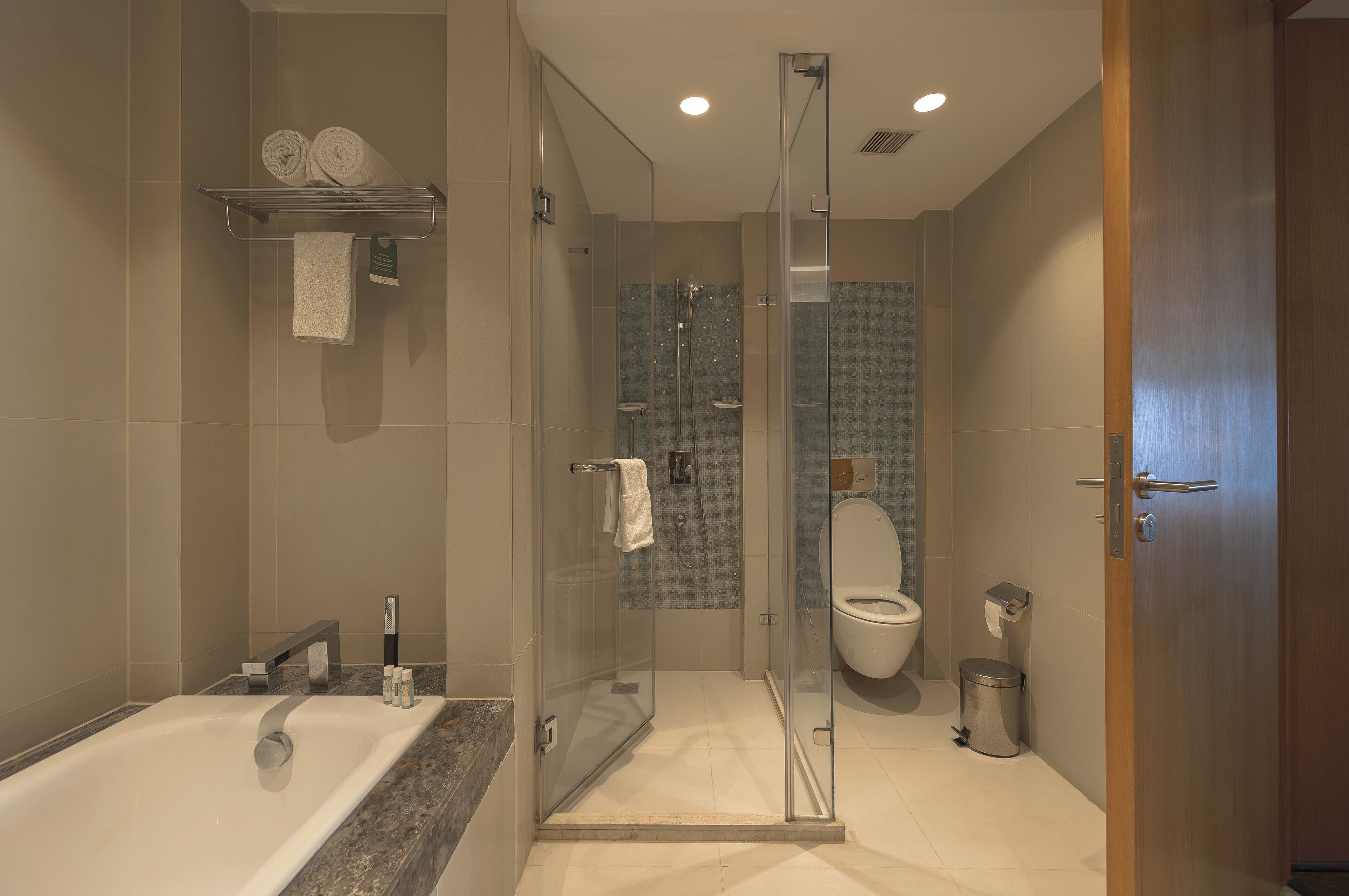 Un baño moderno con ducha envuelta en vidrio, bañera y retrete.