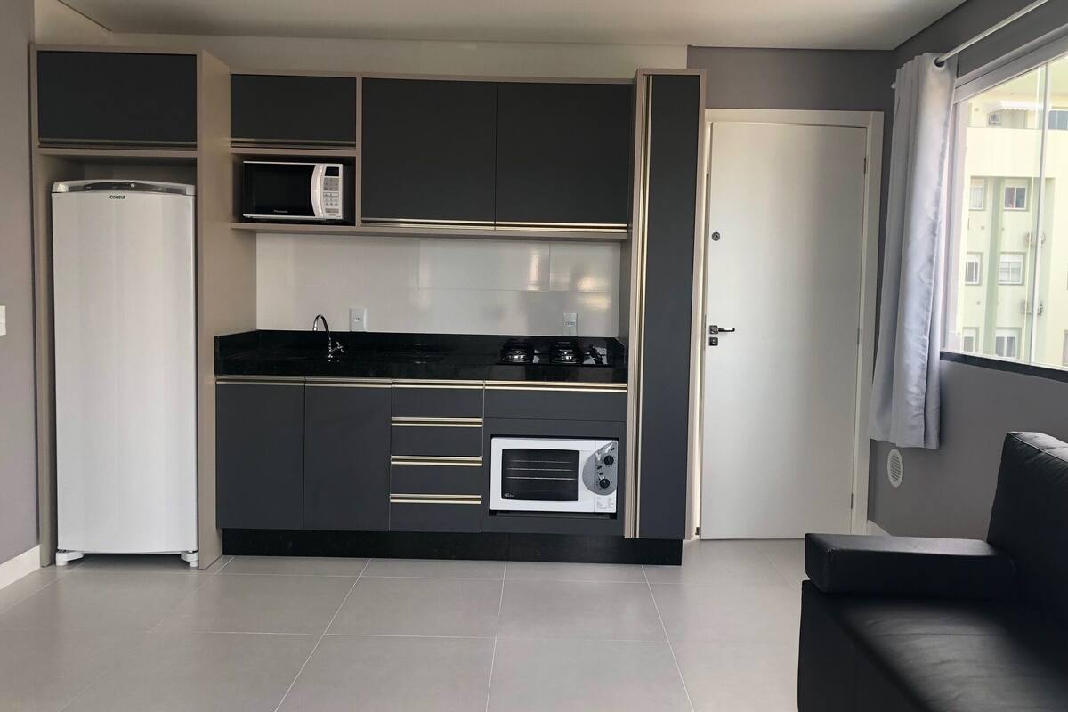 A compact kitchen with a refrigerator, microwave, stove, and oven.