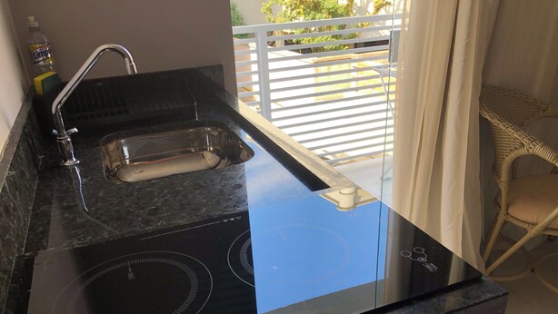 A kitchen with a black induction cooktop, a sink, and a bottle of hand soap. - Lagoinha Beach Residencial (Bombinhas)
