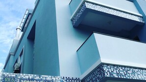 A modern building with a geometric facade, multiple balconies, and a tiled base. - Lagoinha Beach Residencial (Bombinhas)