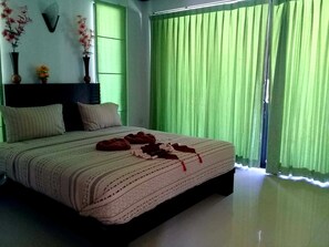 Ein ordentlich bezogenes Bett mit einem gemusterten Bettüberwurf, zwei Kissen und einer roten Decke.