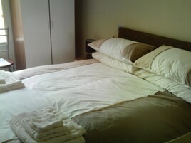 A hotel room with a bed, pillows, a nightstand, and a chair.