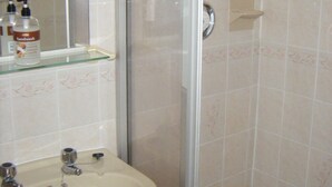 A bathroom with a sink, mirror, and shower area. - Arlingtons (Blackpool)