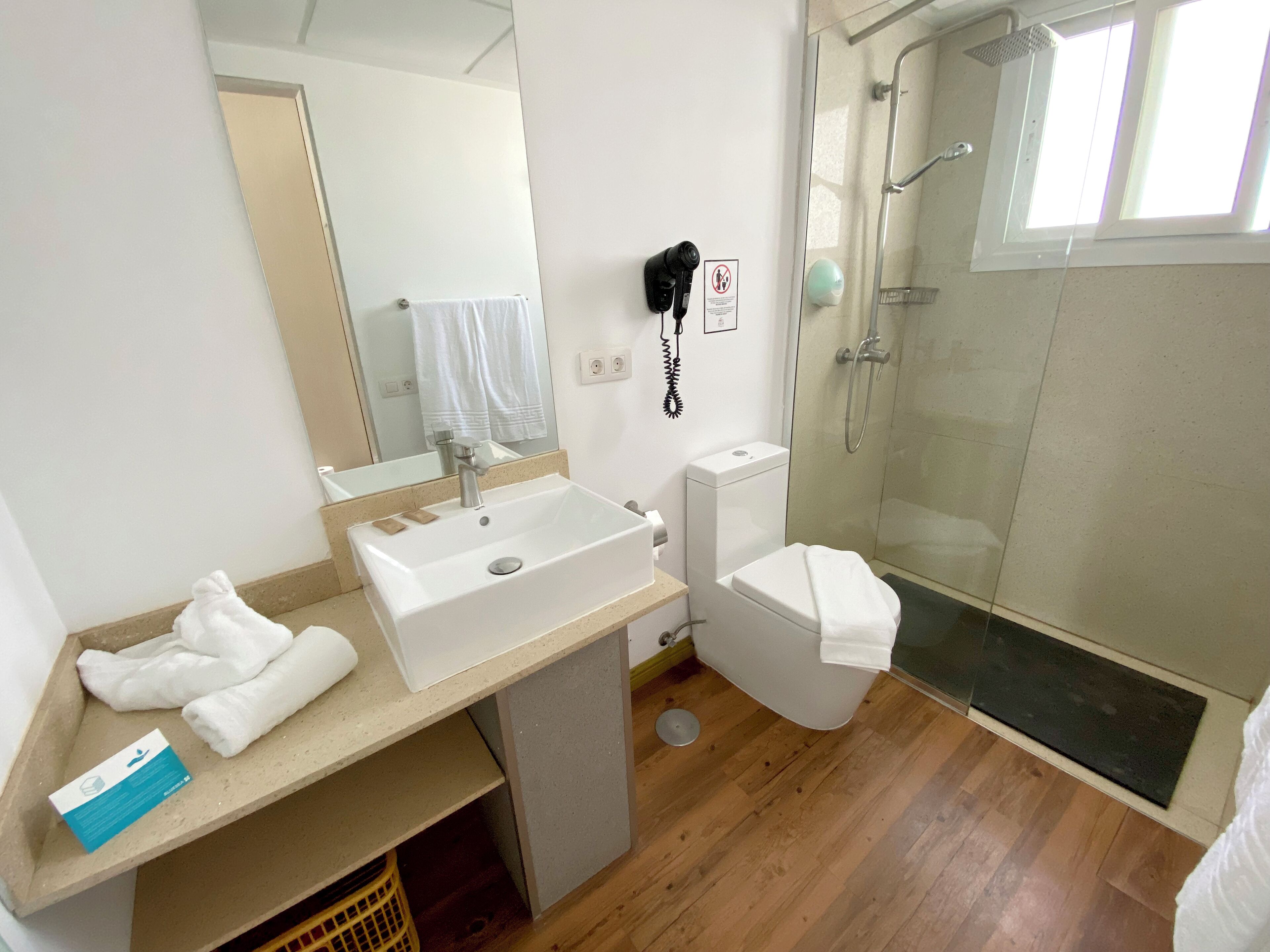 Un baño con un lavabo blanco, inodoro, ducha y toallero.