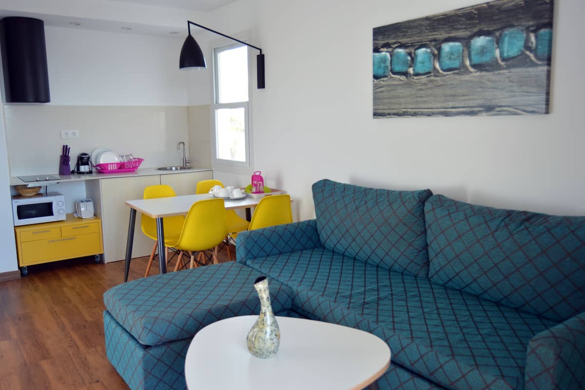 Un espacio habitable compacto con kitchenette, comedor y sofá.