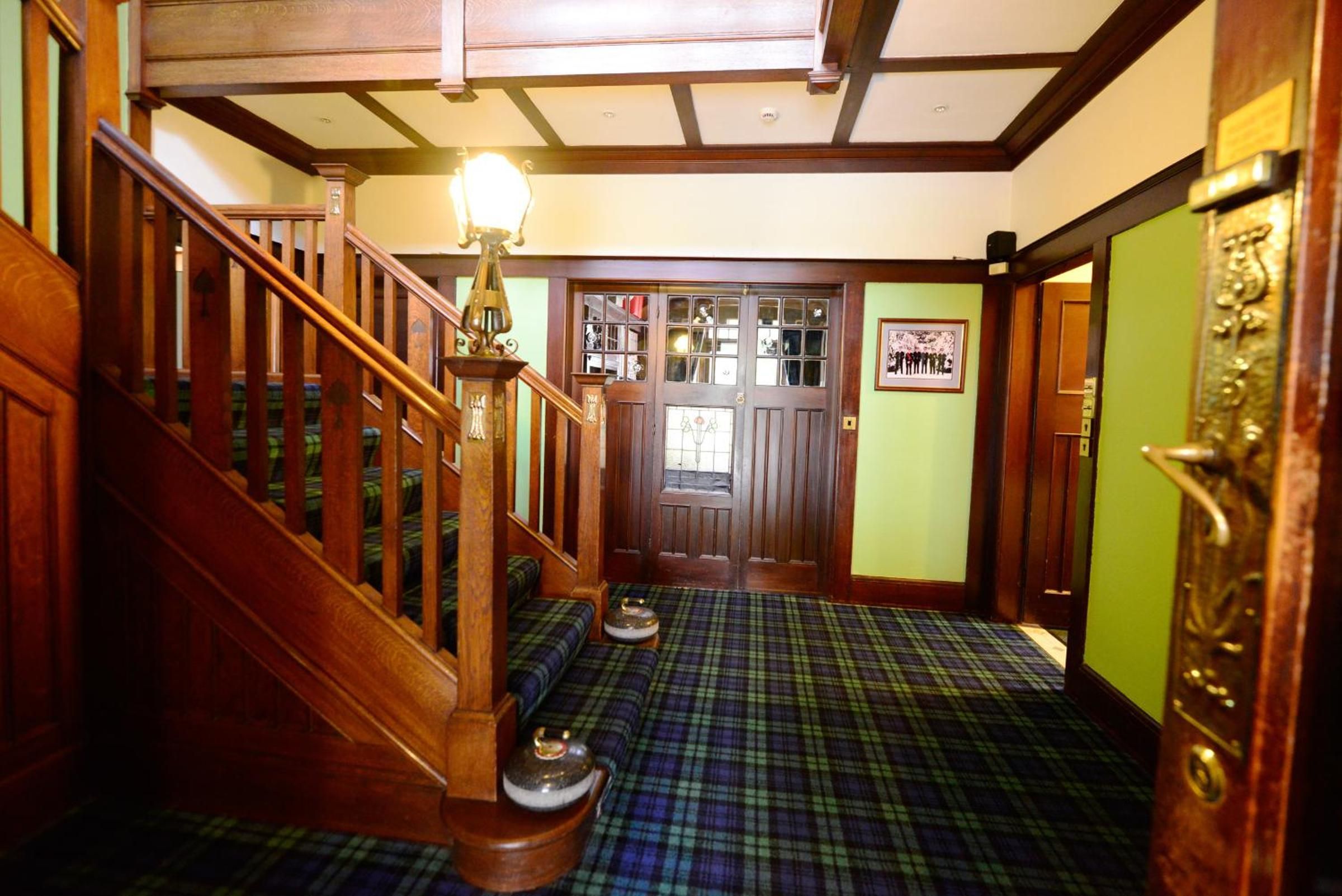 A staircase with a wooden handrail and a light fixture above it.