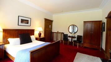 Ein Hotelzimmer mit einem großen Bett, einem Schreibtisch, einem Stuhl, einem Kleiderschrank und einem Spiegel.