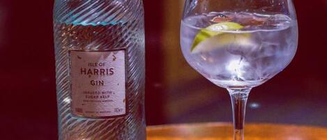 A bottle of gin and a glass with a lime wedge on a wooden surface.