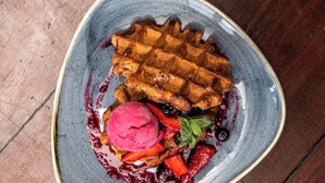 Gofre con frutos rojos y helado sobre un plato de cerámica.