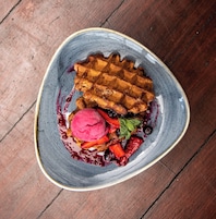 Gofre con frutos rojos y helado sobre un plato de cerámica.