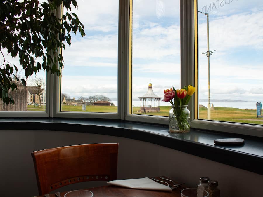 Comedor con vistas a un campo cubierto de hierba y un pabellón, a través de amplias ventanas.