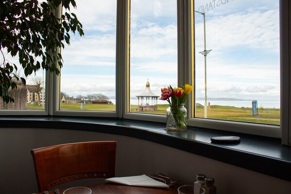 Comedor con vistas a un campo cubierto de hierba y un pabellón, a través de amplias ventanas.