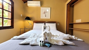 A hotel room with a bed, a nightstand, a lamp, an air conditioner, and a framed picture on the wall. - Pousada Canoas Buzios (Buzios)