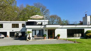A modern two-story house with a garage, a patio with a table and chairs, and a large umbrella. - White Lodge B&B (Lewes)