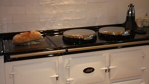 A kitchen with a loaf of bread on a cooling rack, a kettle, and a coffee maker on the counter. - White Lodge B&B (Lewes)