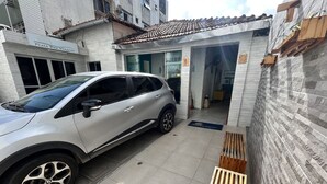 Ein weißes Auto parkt auf einer schmalen Auffahrt mit einem Ziegeldach und einer Steinmauer an der Seite.