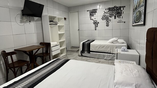 Ein Hotelzimmer mit Bett, Schreibtisch, Stuhl, Kleiderschrank und Wandkarte.