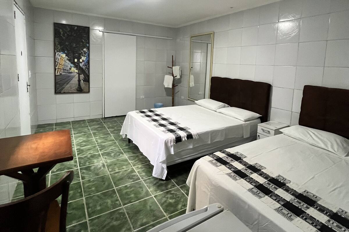 A hotel room with two beds, a desk, and a chair.